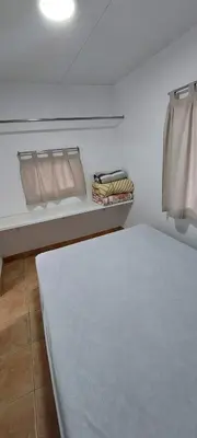 a room with a bed and a shelf with towels at Camping Barraquetes in Sueca