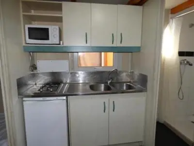 a small kitchen with a sink and a microwave at Camping Barraquetes in Sueca