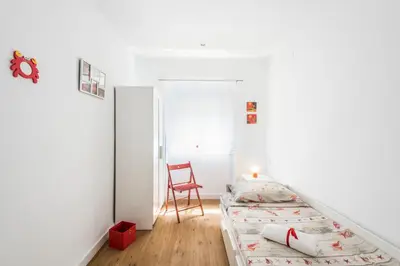 a bedroom with two beds and a red chair at El Coral Apartment Valencia in Valencia