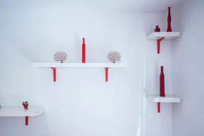 a white shelf with red vases on a wall at El Coral Apartment Valencia in Valencia