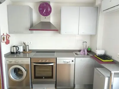 a kitchen with a washing machine and a clock on the wall at Apartamento en la Ciudad de las Artes y las Ciencias in Valencia
