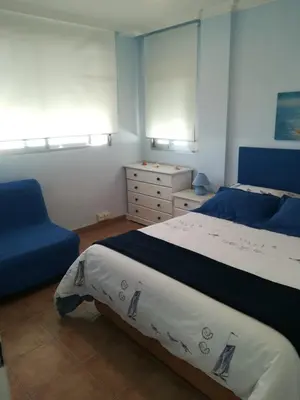 a bedroom with a bed and a blue chair at apartamento junto al mar in Cullera