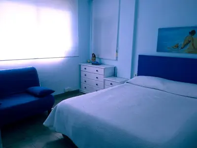 a bedroom with a bed and a chair and a window at apartamento junto al mar in Cullera