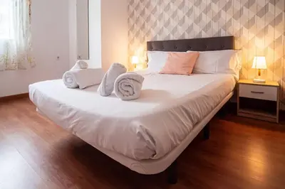 a bedroom with a large white bed with towels on it at Flats Burjasot in Valencia