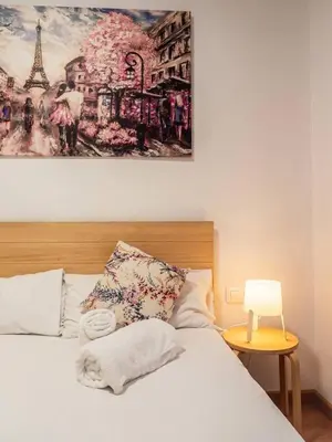 a bedroom with a white bed with a painting on the wall at Flats Burjasot in Valencia
