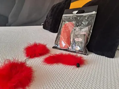 two red pom poms on a bed with a bag at Hotel Luve in San Antonio de Banageber