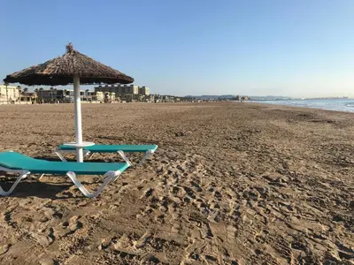 a chair and an umbrella on the beach at Avenida Mare Nostrum 7 Patacona Beach Breakfast items in the home in Valencia