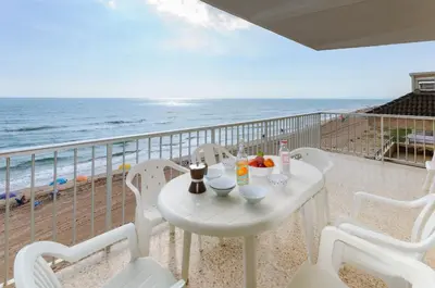 a white table and chairs on a balcony with the beach at Turia in Tavernes de Valldigna