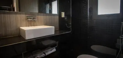 a bathroom with a white sink and black tiles at Cosy Rooms Embajador in Valencia