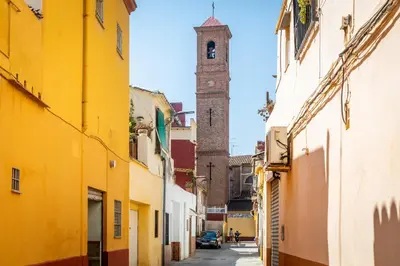 a narrow street with a clock tower in the distance at Travel Habitat Cabanyal in Valencia