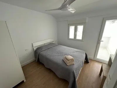 a bedroom with a bed with a gray blanket and two windows at Casa Quintero Valencia Playa Cabañal in Valencia