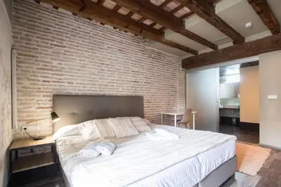 a bedroom with a brick wall and a large bed at Cosy Rooms Bolsería in Valencia
