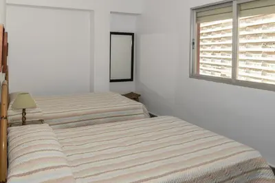 a white bedroom with two beds and a window at EL RACO- C, 8-16 in Cullera