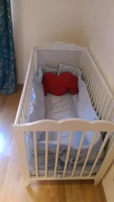 a white crib with a heart shaped pillow in it at Apartamento San Antonio in Sedaví