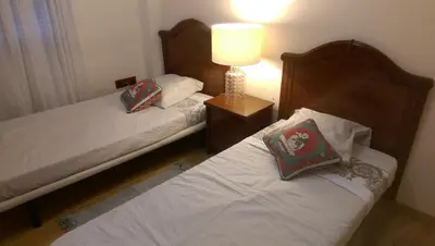 two beds in a bedroom with a lamp on a table at Apartamento San Antonio in Sedaví