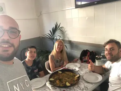 a group of people sitting at a table with a plate of food at Habitación privada a 1500 metros de la playa in Valencia