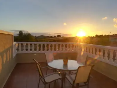 a table and chairs on a balcony with a sunset at Casa Tambor in Puebla de Vallbona