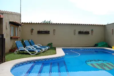 a swimming pool with lounge chairs next to a house at Casa Tambor in Puebla de Vallbona