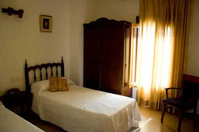 a bedroom with a white bed and a window at Hotel Álvarez in Tuéjar