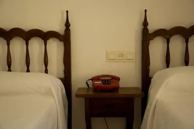 a room with two beds and a radio on a table at Hotel Álvarez in Tuéjar