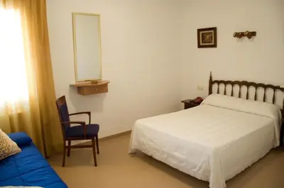 a bedroom with a bed and a chair and a mirror at Hotel Álvarez in Tuéjar