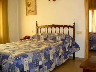 a bedroom with a bed with a blue and white quilt at Hotel Álvarez in Tuéjar