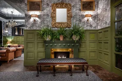 a living room with a fireplace and a mirror at NH Collection Colón Valencia in Valencia
