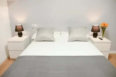 a white bed with two night stands and two lamps at Piso en La Ciudad de Artes in Valencia