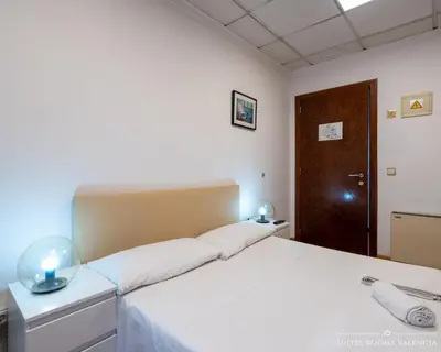 a bedroom with a white bed and a wooden door at Suites Rooms Valencia in Valencia