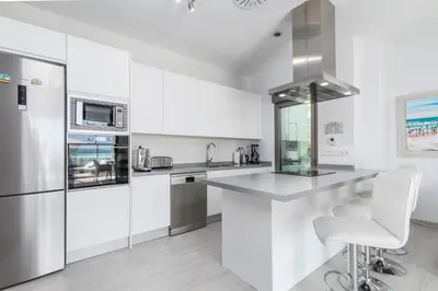 a kitchen with white cabinets and a stainless steel refrigerator at Luxury Beach Front Apartment with Pool in Valencia