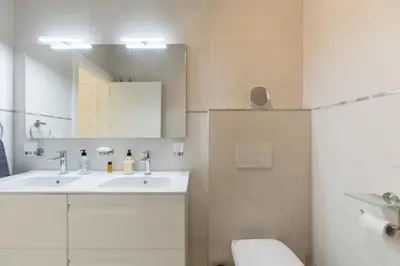 a bathroom with a sink and a toilet and a mirror at Luxury Beach Front Apartment with Pool in Valencia