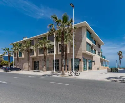 a building with palm trees in front of a street at Luxury Beach Front Apartment with Pool in Valencia