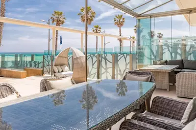 a patio with a table and chairs and the ocean at Luxury Beach Front Apartment with Pool in Valencia