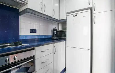 a kitchen with white cabinets and a white refrigerator at One-Bedroom Apartment In La Pobla De Farnals in Puebla de Farnals