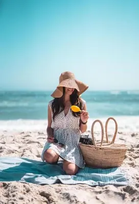 a woman sitting on the beach with a picnic basket at Valencia Beach room with private bathroom coliving in Port Saplaya