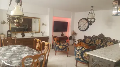 a living room with a table and chairs and a clock at el piso perfecto in Puerto de Sagunto