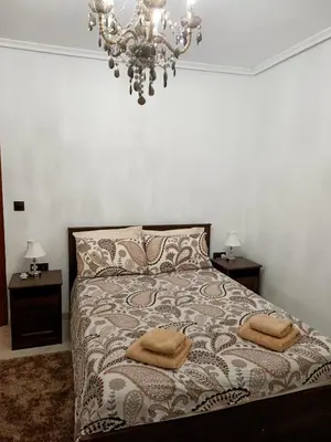 a bedroom with a bed with two night stands and a chandelier at el piso perfecto in Puerto de Sagunto