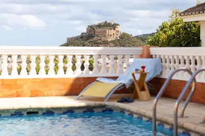 a resort with a pool and a castle in the background at Casa Rural La Torreta in Corbera de Alcira