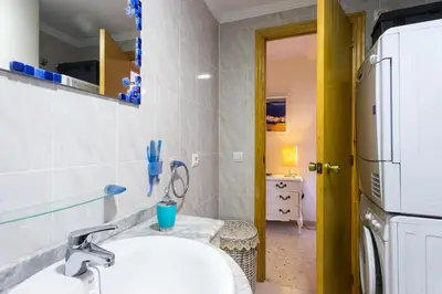 a bathroom with a sink and a refrigerator at ApartUP Saplaya Harbour in Alboraya