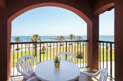 a white table and chairs on a balcony with the ocean at ApartUP Saplaya Harbour in Alboraya
