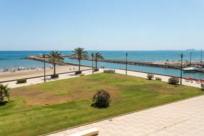 a park next to the beach with palm trees and the ocean at ApartUP Saplaya Harbour in Alboraya