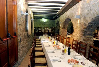a row of tables in a room with a stone wall at Hotel Restaurant Verdià in Sueras