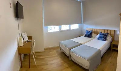 a bedroom with two beds and a desk and a television at Nanit Valencia Hostel in Valencia