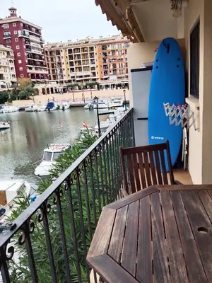 a table and a surfboard on a balcony with a river at Beach Apartment with beautiful view in Port Saplaya