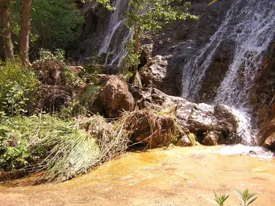 a waterfall on the side of a mountain with trees at Casa Rural La Tia Rosa in Chulilla