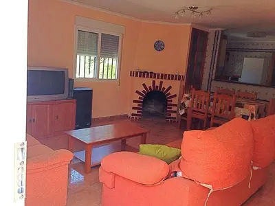 a living room with an orange couch and a table at Chalet en el Monte con Piscina in Sagunto