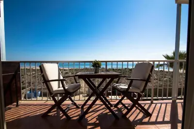 a table and two chairs on a balcony with the ocean at Perfecto apto a orillas del mediterráneo / 4PAX in El Perellonet