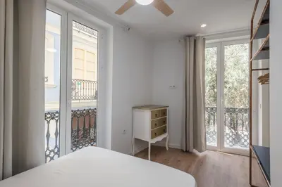 a bedroom with a bed and two large windows at L'Arbre in Valencia