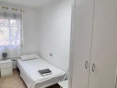 a small white room with a bed and a mirror at Plaza Sainetero Arniches in Valencia