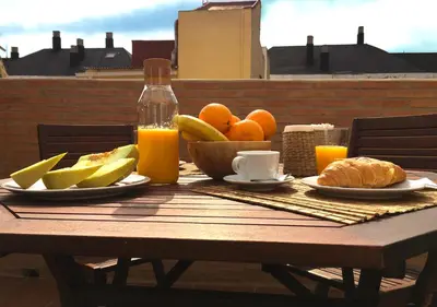 a wooden table with a bowl of fruit and orange juice at Ático cerca del mar in Valencia
